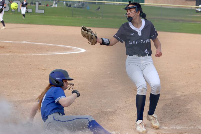 Cary-Grove’s Addy Green, right, looks for the toss as Burlington Central’s Antonina Garcia slides safely into home in varsity softball at Cary Monday.