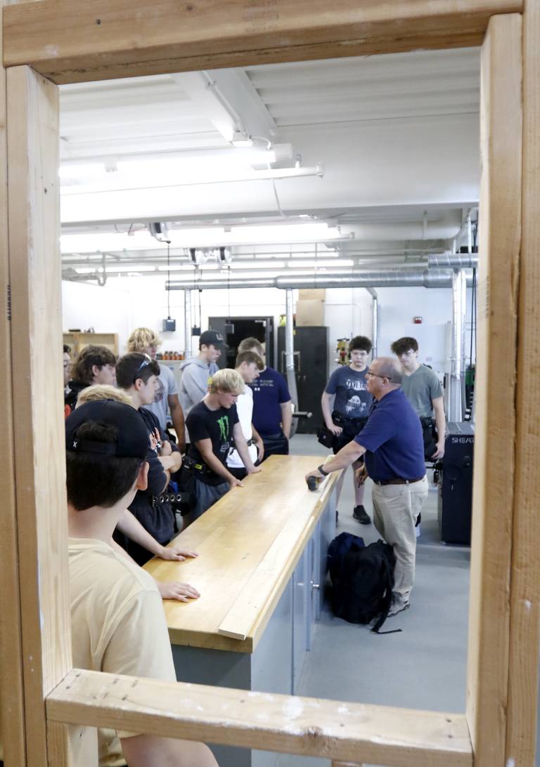 Dan Rohman teaches his construction trades students how to measure out a board to build a stud wall on Tuesday, Aug. 30, 2022, during class at McHenry High School. The students in the class will build the tiny shops that will house incubator retail businesses on McHenry's Riverwalk at Miller Point.