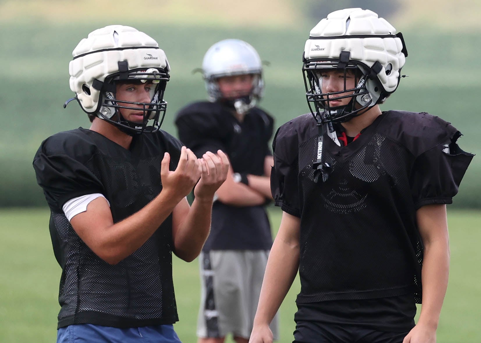 Kaneland’s Vinny McDonald (left) talks to Dylan Sanagustin about receiving kicks during practice Friday, Aug. 16, 2024, at the school in Maple Park.