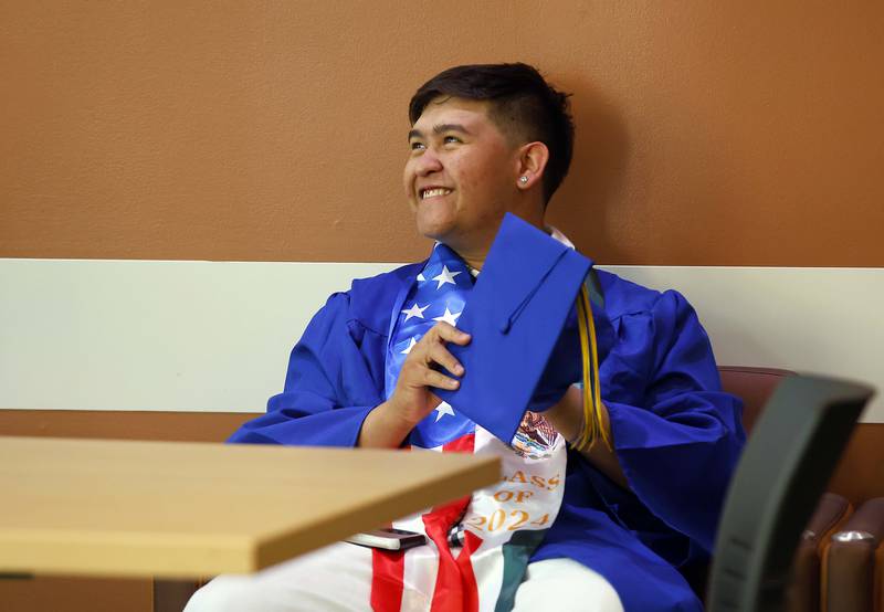 Wheaton North High School graduate Jose Andrade adjusts his mortar board before his graduation ceremony Saturday, May 25, 2024 in the Physical Education Center of College of DuPage in Glen Ellyn. Andrade is wearing a Mexican/American sash, as a symbol of his heritage.