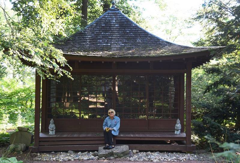 Bobbi Higham, a member of the Geneva Garden Club, sits near the Japanese Tea Garden teahouse at Fabyan Forest Preserve in Geneva. Higham and other club members have been working on restoration at the site.