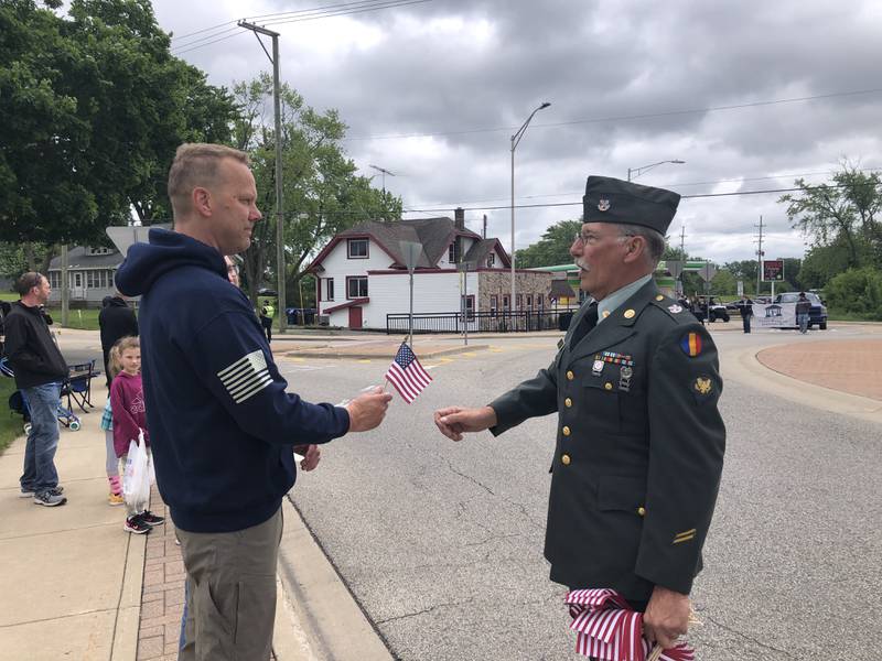 Carl Kamienski hands Kevin Knutilla a flag during the Johnsburg Memorial Day parade Monday May 27, 2024.