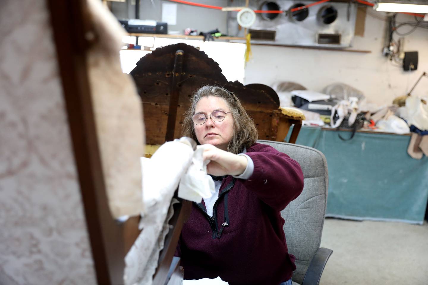 Ruth Scott applies wax to a piece of furniture at Valley Upholstery and Design in Batavia. Following the September 2021 death of Valley Upholstery and Design owner Jesse Pitts, his family and friends, including daughter Jesseca Watson, wife Eloise and friend Ruth Scott, have been working diligently to complete his customers’ projects and keep the shop open.