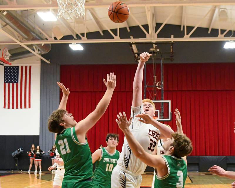 Indian Creek's Isaac Willis (33) goes up for a shot while being defended by Dwight's Luke Gallet (21) and teammate Dwight's Conner Telford (3) during the regional quarterfinal game Monday, Feb. 19, 2024, held at Indian Creek High School.