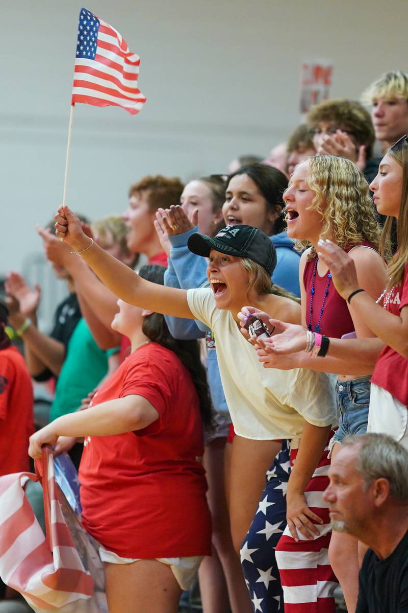 Sandwich senior Hanna Decker (17) holds the American Flag while cheering on her team during a volleyball match against Plano at Sandwich High School on Tuesday, Sep 10, 2024.