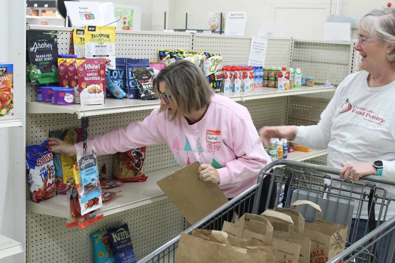 Crystal Lake Food Pantry volunteers Heather Marts and Joanna Bradshaw gather food for a client order.