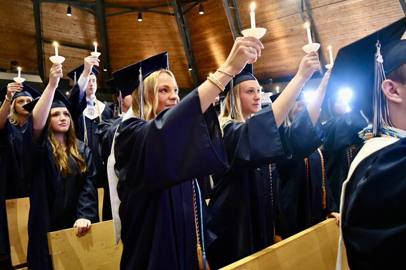 Nazareth Academy graduates Katherine Mangan, Emma Heery and Hannah Hesser raise the alumni flame during the school’s commencement ceremony at Christ Church in Oak Brook on Sunday, May 19, 2024.