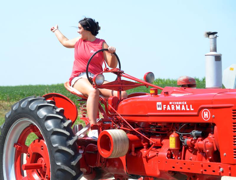 Nadezda Cater, 18, of Dixon, waves to her sister from her grandparents' 1942 Farmall tractor during the the Living History Antique Equipment Association's tractor drive on Saturday. About 40 tractors took part in the ride that started at the association's show grounds in Franklin Grove and traveled to Oregon and back.