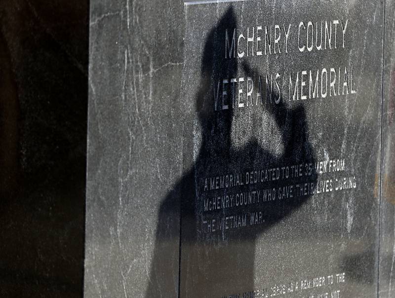 Veteran Carl Kamlenski’s shadow is cast onto the McHenry County Veterans Memorial as he salutes McHenry County veterans who died in the Vietnam War during the “Voices from Vietnam,” program on Friday, March 29, 2024, at the McHenry County Government Administration Building in Woodstock. The program was the first time that McHenry County honored Vietnam veterans on Vietnam War Veterans Day. The day, that was created by federal law enacted in 2017, honors the more than 2.7 million American men and women who served in Vietnam.