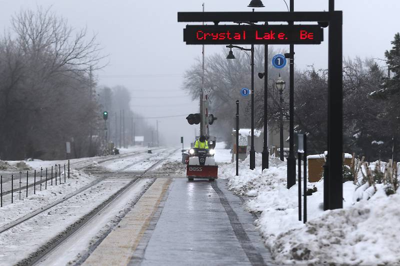 A worker from Ringers Landscape Services,  treat sidewalks near the Downtown Crystal Lake Metra station on Tuesday, Jan. 23, 2023. Residents throughout northern Illinois woke up to icy and slippery roads.