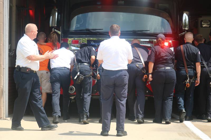 DeKalb firefighters, city officials and community members push fire engine No. 2 into the garage at fire station No. 2 Friday, Aug. 4, 2023 as part of a dedication ceremony.