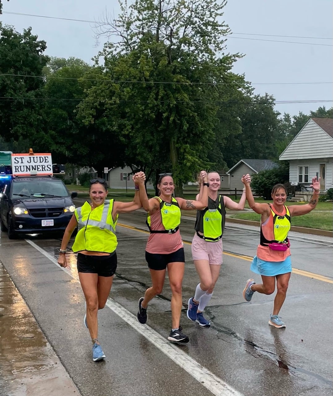 La Salle Peru runners join hands in the rain on their way to the Peoria Civic Center.