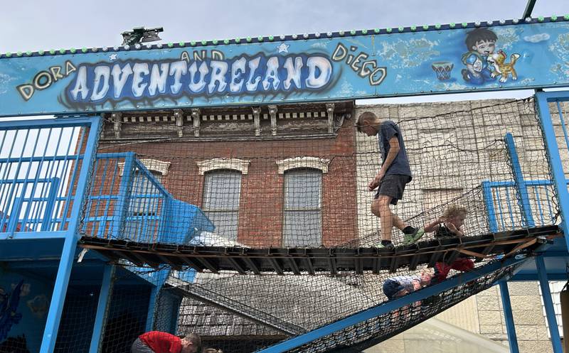 Sam Person, 11,  of Polo, crosses the swinging bridge on the Adventureland carnival ride after helping some younger kids navigate the course during Town & Country Days on Saturday, June 15, 2024.