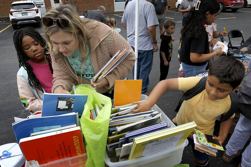 Suzanne Evenson helps JaKayla Ruffin find some books to read during a Woodstock School District 200 Back to School Coming to You event at Northwood Middle School on Tuesday, Aug. 6, 2024. The location was one of twelve stops on the tour that gave out backpacks and school supplies, provided registration help and computer repair.