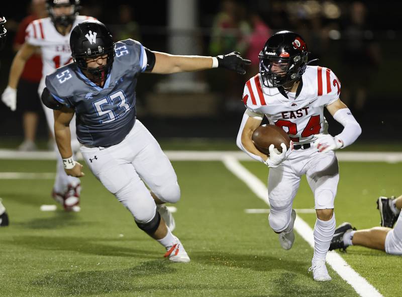 Glenbard East's Valentino Heredia (24) runs against Willowbrook's Josh Puknaltis (53) during the varsity football game between Glenbard East and Willowbrook high schools on Friday, Sep. 30, 2024 in Villa Park.