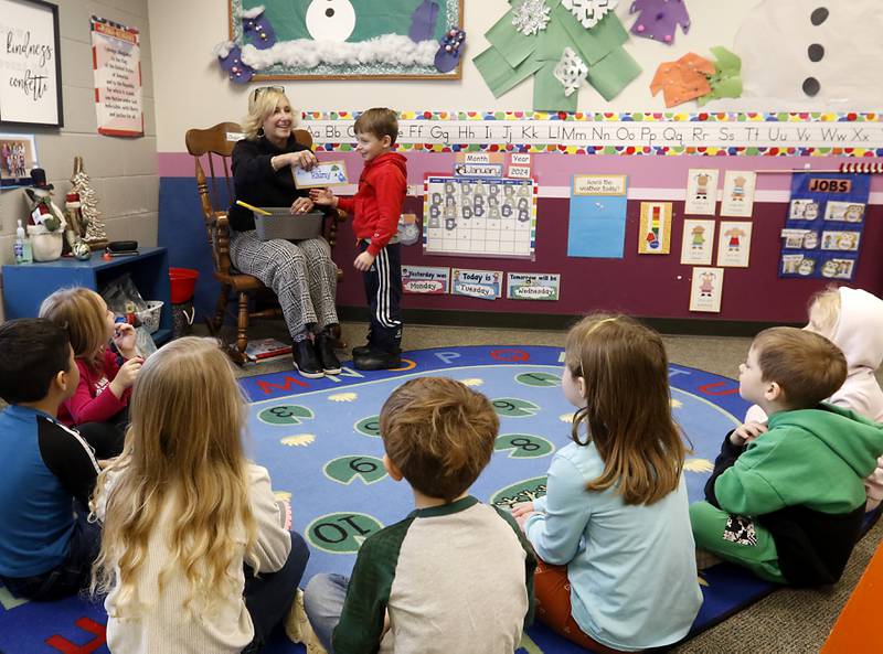 Teacher Lisa Knoeppel hands Mason the rainy weather sign to hang up on Tuesday Jan. 23, 2024, at the Purple Moose in Crystal Lake. The preschool will close down after the current school year finishes in June, unless the school can find another location after the Shiloh Church decided not to renew the preschool's lease.