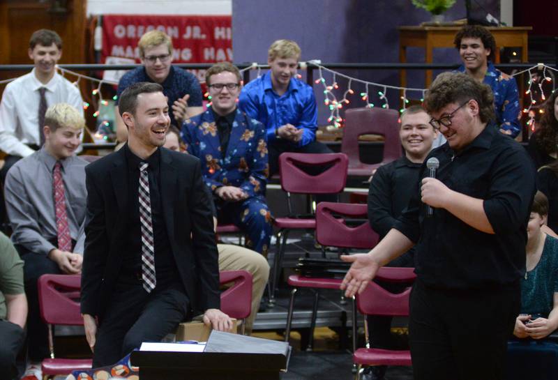 Oregon High School Choir Director Zach Hall sits on the Christmas present he received as Brady Davis tells him it is a new chair. The choir presented Hall with the gift during the OHS Christmas Concert held Sunday, Dec. 17, 2023 at Oregon High School.