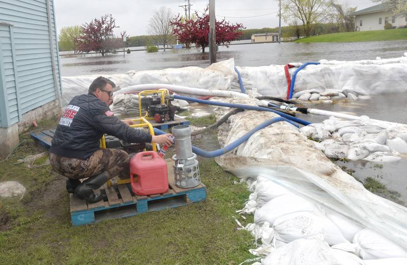 Jacob Helms, a volunteer firefighter with the Savanna Fire Department, refills a gas can on Sunday in preparation of refueling transfer pumps west of Main Street in the city's downtown. Firefighters along with volunteers and inmates from Kewanee and East Moline, constructed the wall with 46,000 sand bags in anticipation of river levels rising past the 21-foot mark. The pumps were beung used to pump floodwaters that seeped under the bags.