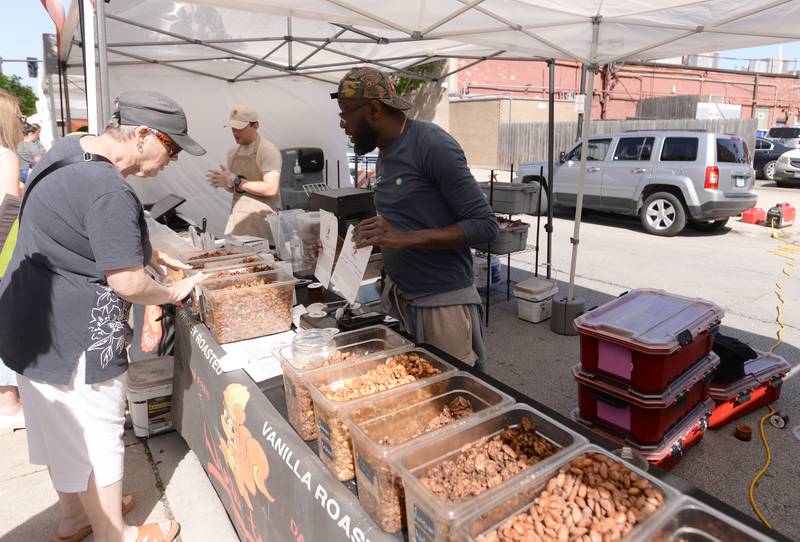 Karen Teeling of Indian Head Park taste tests some of the nuts from Nuts to Go owner Maurice Reynolds during the LaGrange Farmers Market Thursday June 7, 2024.