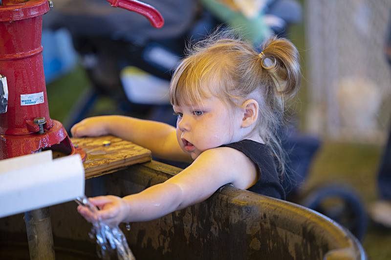 Ellie Engelkens, 2, of Milledgeville reaches out to touch the water in a duck race game Saturday, August 12, 2023 at the Carroll County Fair. A Discovery Farm tent allowed both kids and adults to explore about farming with hands on learning.