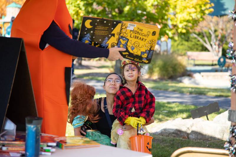 Helen (5), left,  Kathy, middle, and Hannah (3) Kud of Glen Ellyn listen to a story read aloud by Kate Easley during Boo Bash at the Glen Ellyn Park District on Saturday, Oct. 22, 2022.