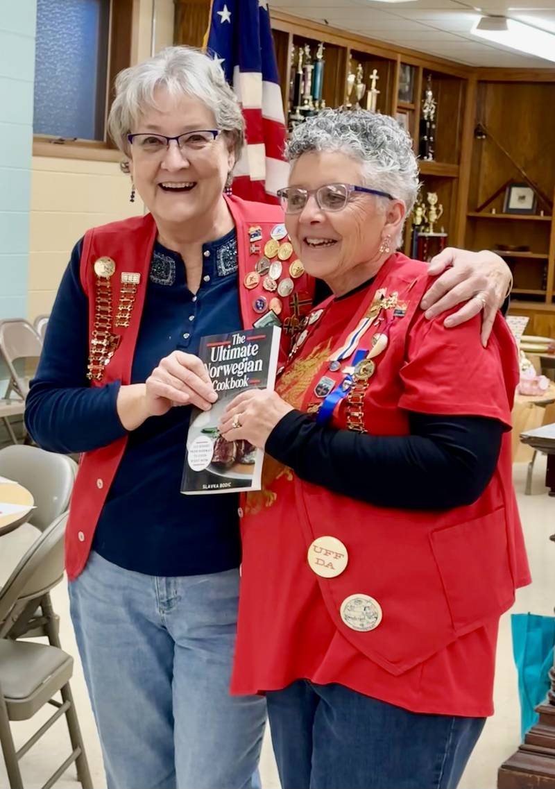 Oswego resident Jerri Lynn Baker, right, receives a first-place soup recipe award from Barb Johnson, Yorkville, in Sons of Norway Polar Star Lodge 5-472's annual Souper Bowl contest Feb. 4. Baker's award was a copy of "The Ultimate Norwegian Cookbook." Johnson later added Baker's name to the contest traveling trophy, a gold-colored soup pot.