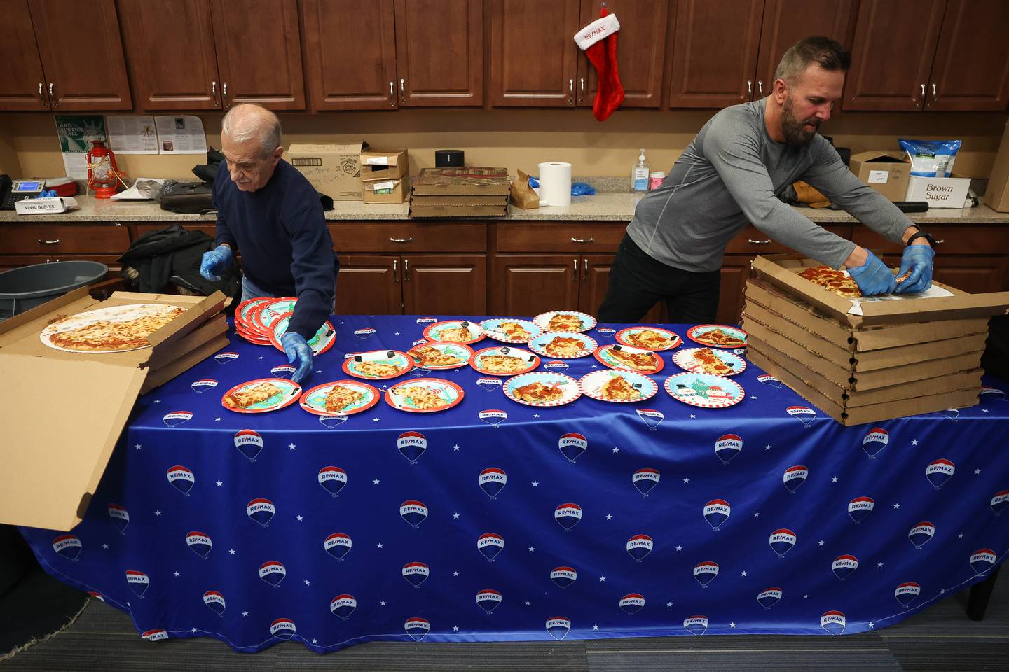 Volunteer Frank Bati and ReMax’s Ryan Behrens prepares the pizza at the Boys & Girls Club Joliet pizza party on  Saturday, Dec. 18, 2023.