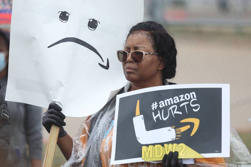 An Amazon employee holds a sign with the Amazon logo upside down to represent a sad face at a rally outside the Amazon MDW2 facility on Tuesday, October 11th in Joliet. Amazon employees of MDW2 are teaming with Workers for Justice, a nonprofit organization supporting warehouse workers, to demand a safer work place and jobs that offer a living wage.