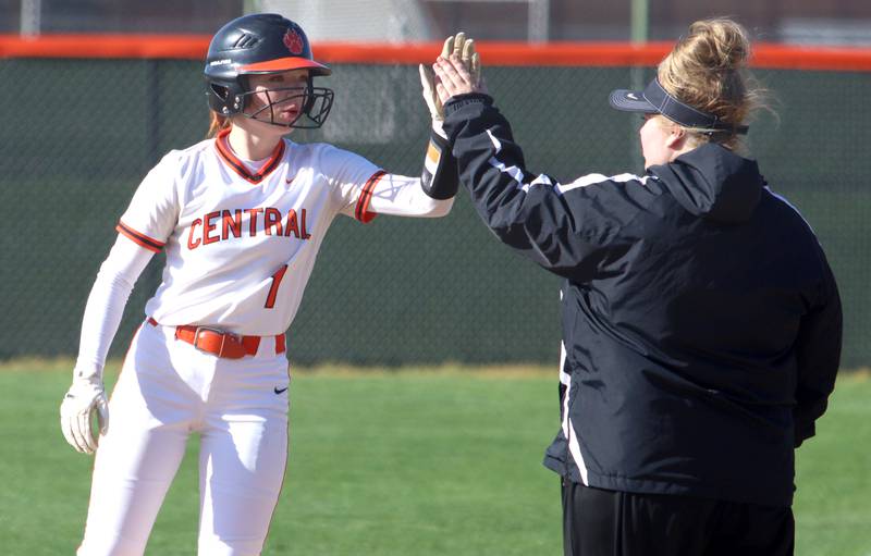 Crystal Lake Central’s Makayla Malone is greeted at first base after a single against Woodstock North in varsity softball at Crystal Lake Friday.