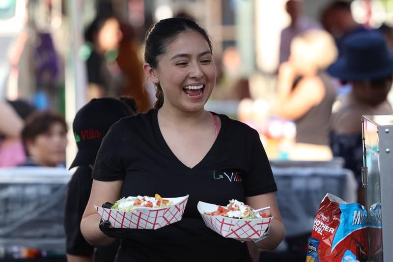 Mary Carmen hands out a order of nachos from the La Villa food tent at Salsa Fest on Friday, June 9, 2023 in Downtown Joliet.