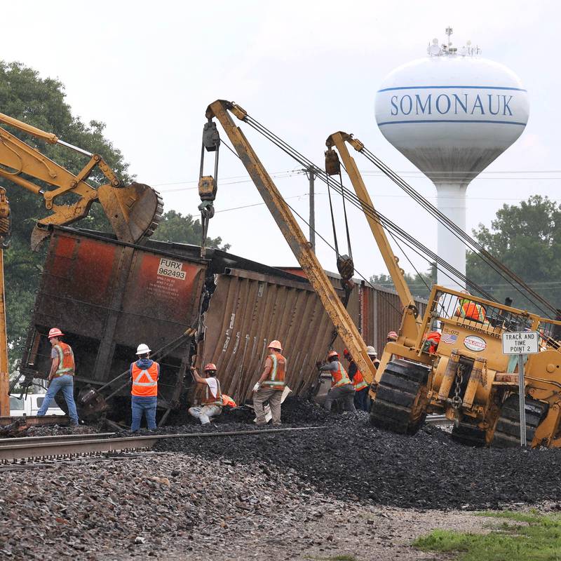 Cranes and a loader upright a tipped over coal car after a BNSF Railway train traveling east derailed Wednesday, July 10, 2024, near Route 34 on the west side of Somonauk.