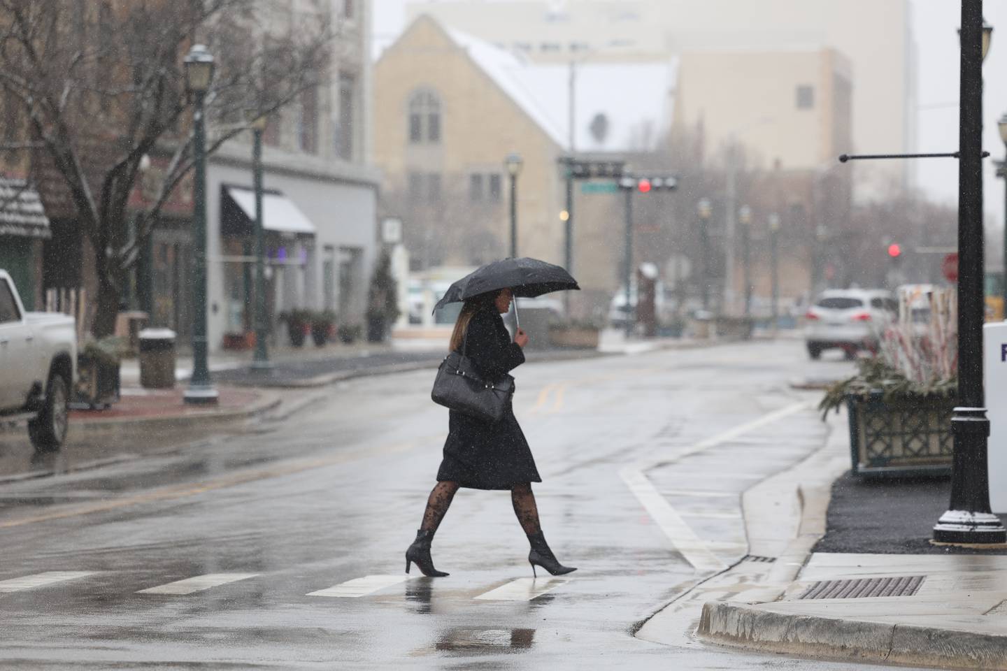 A pedestrian crosses North Chicago Street as snow falls Friday morning on Feb. 16th, 2024 in Joliet.