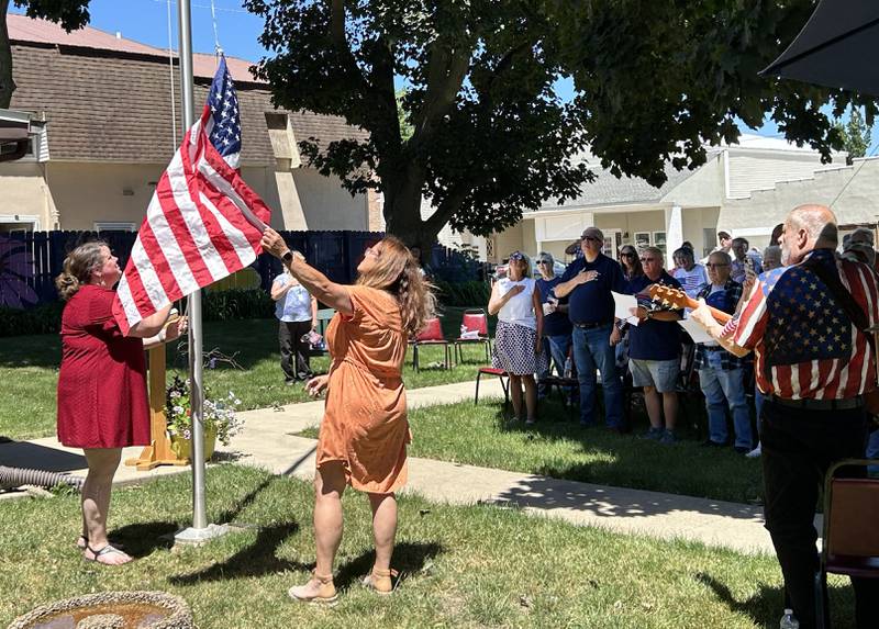 Members of the crowd watch as Mt. Morris and Senior and Community Center Executive Director Melissa Rojas (left) and her assistant, Kristine Wachs, raise a new Ameircan flag during a Flag Day ceremony on Friday, June 14, 2024.