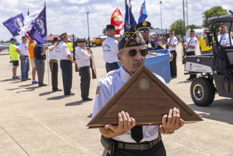 Peru Veterans Memorial Guard member Phillip Valle carries a case containing a folded flag that was on one of many that were placed aboard a TBM Avenger for a memorial flight during the TBM Avenger Reunion and Salute To The Veterans at Illinois Valley Regional Airport on May 18, 2024.