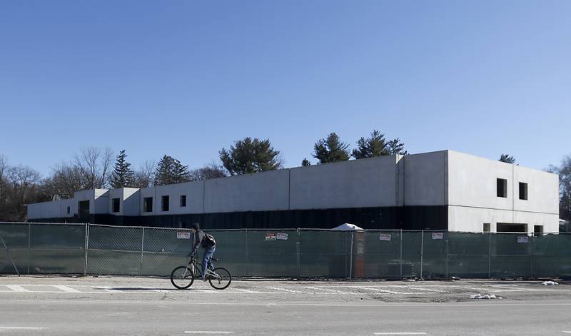 A person rides their bicycle past a partially constructed five-story, 100-unit apartment complex at 401 Algonquin Road near Route 14 in Fox River Grove on Tuesday, March 16, 2023. Contractors allege in court records that they haven't been paid for work on the building, which had drawn the ire of neighbors and concerns from the Fox River Grove Fire Protection District.