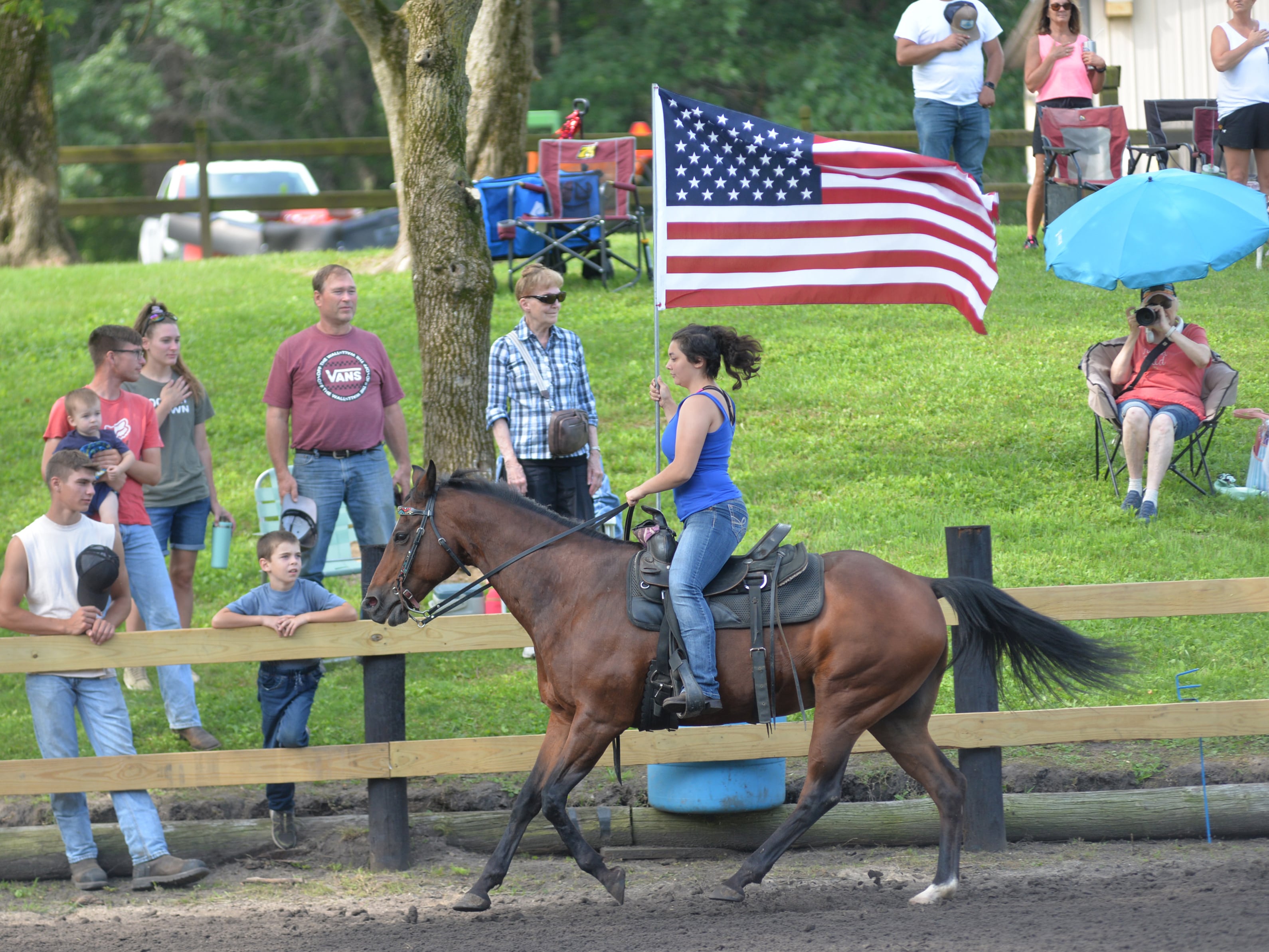 Evie Helton of Sycamore and a member of the Ogle County 4-H Horse Drill Team, carries the American flag as the National Anthem is played at the start of the Rock River Trail & Horseman Association's Grand Opening Show on Saturday, July 20, 2024. The show was held in the newly refurbished horse arena located in Franklin Creek Natural Area just north of Franklin Grove.