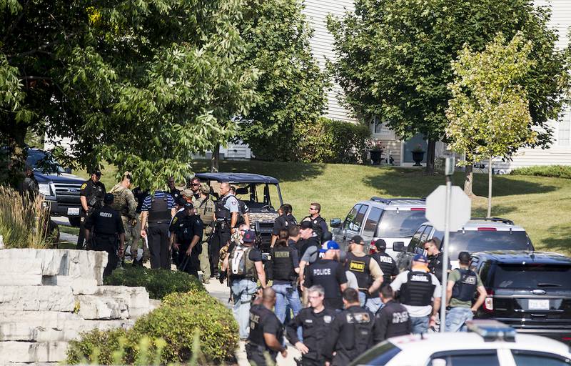 Law enforcement members sweep an area near Frontage Road and Fox Ridge Drive in Fox Lake during a manhunt Tuesday for three people suspected in the killing of a Fox Lake police officer.