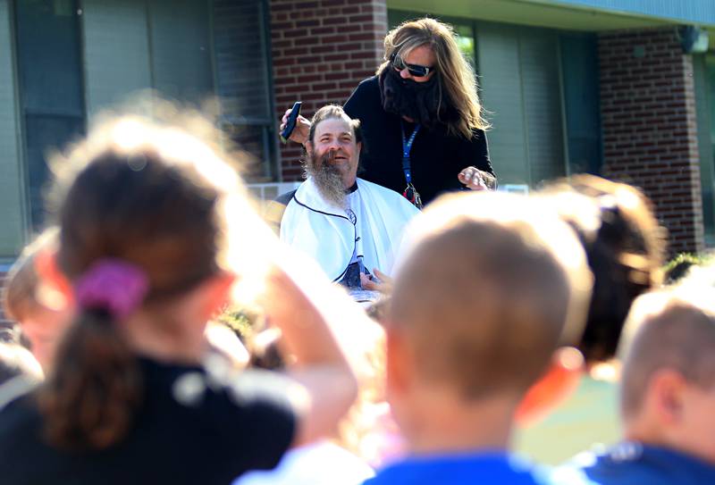 Custodian Bob Espel has his head shaved by staff member Ginger Barnes on Wednesday, May 22, 2024 at Douglas Elementary School in Princeton. Students raised more than $3.332 in the past few weeks. All proceeds will go to the new landscaping around the Douglas building, with the first round of plantings to take place with students present this Thursday, May 23. Using funds from the Preschool for All grant the school has purchased new age-appropriate playground equipment to promote physical activity, creativity and social interaction.