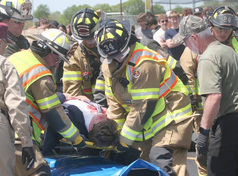 Granville firefighters place Putnam County High School student Eric Vipond into a tarp as Putnam County Corner Bob Cofoid (right) assesses during a "mock prom" scene through the Putnam County Corner's Awareness Program on Friday, May 3, 2024 at Putnam County High School.  Putnam County Fire and EMS units, PC Sheriff, and OSF Lifeflight crew conducted a drill crash scene. The school's prom is Saturday. The program helps students make good choices on prom night.