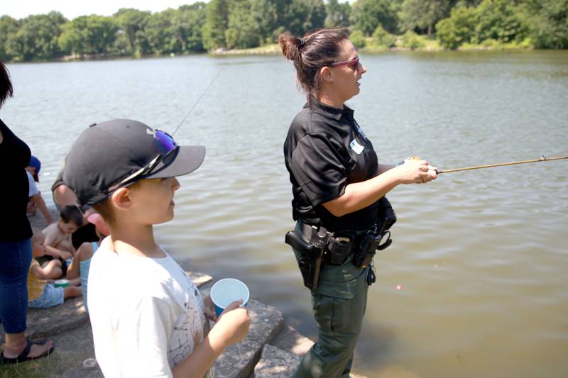 DuPage Forest Preserve Police Officer Kim Eversole of Winfield fishes with her son, Ryker Priest, 10, at Herrick Lake Forest Preserve during the DuPage Forest Preserve Police Cops and Bobbers event in Wheaton on Wednesday, June 19, 2024.