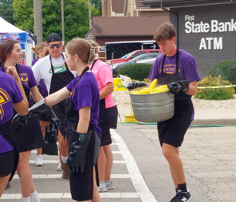 Volunteers transport sweet corn in buckets from the boiler to the distribution area Sunday, Aug. 13, 2023, during the Mendota Sweet Corn Festival.