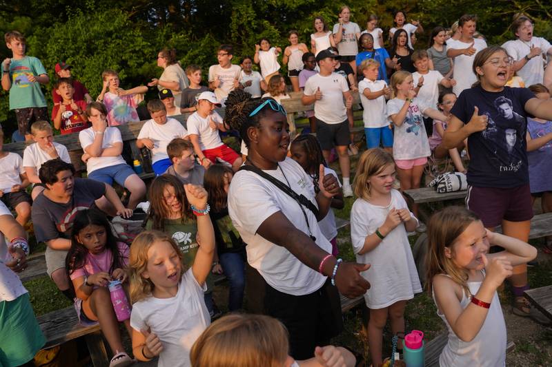 Counselor Kendra Ashong, center, sings a song with other campers, Thursday, June 20, 2024, at YMCA Camp Kern in Oregonia, Ohio.As the first heat wave of the season ripples across the U.S., summer camps are working to keep their children cool while still letting the kids enjoy being outside with nature. (AP Photo/Joshua A. Bickel)