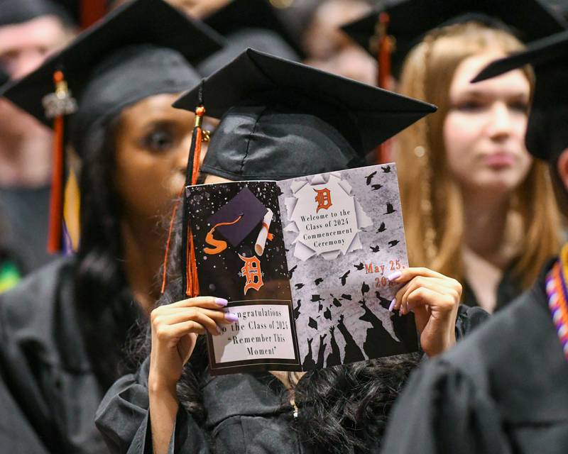 A DeKalb High School graduate reads through the program during the 2024 commencement ceremony on Saturday, May 25, 2024, at the Northern Illinois University Convocation Center in DeKalb.
