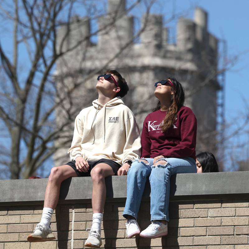 TJ McCann, a sophomore at Northern Illinois University from Carol Stream, and Jackie Tovar, a sophomore from Chicago, watch the eclipse Monday, April 8, 2024, from the back balcony of Founders Memorial Library at NIU. Attendees were treated to perfect weather to watch the rare celestial event.