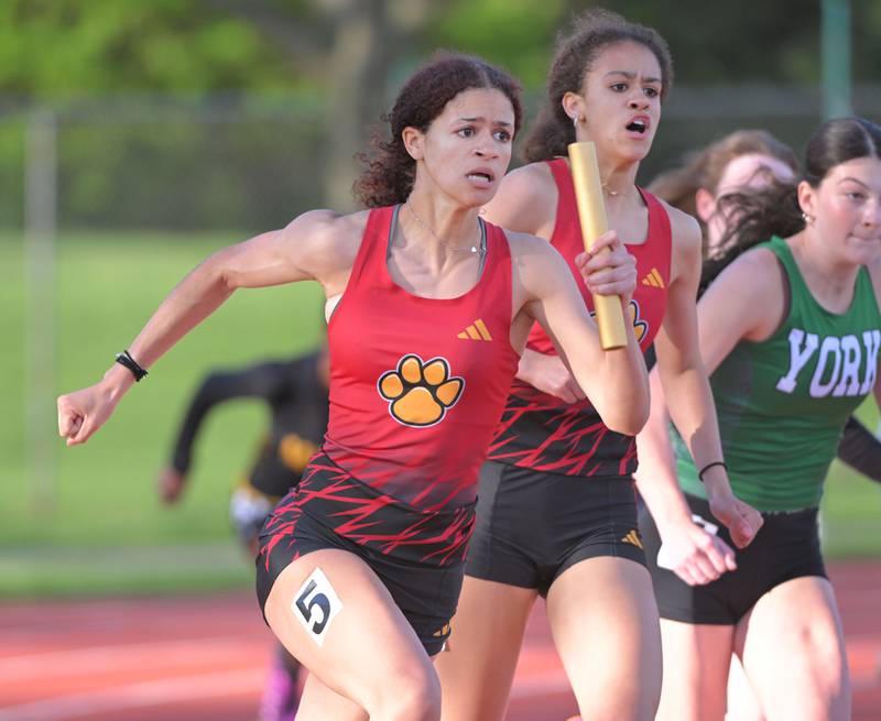 Mariah Wilson takes the baton from her twin Madison, who yells encouragement, on her way to second place overall in the 4x100 meter-relay for Batavia high School at the Lake Park Class 3A girls track and field sectional meet on Friday, May 10, 2024.