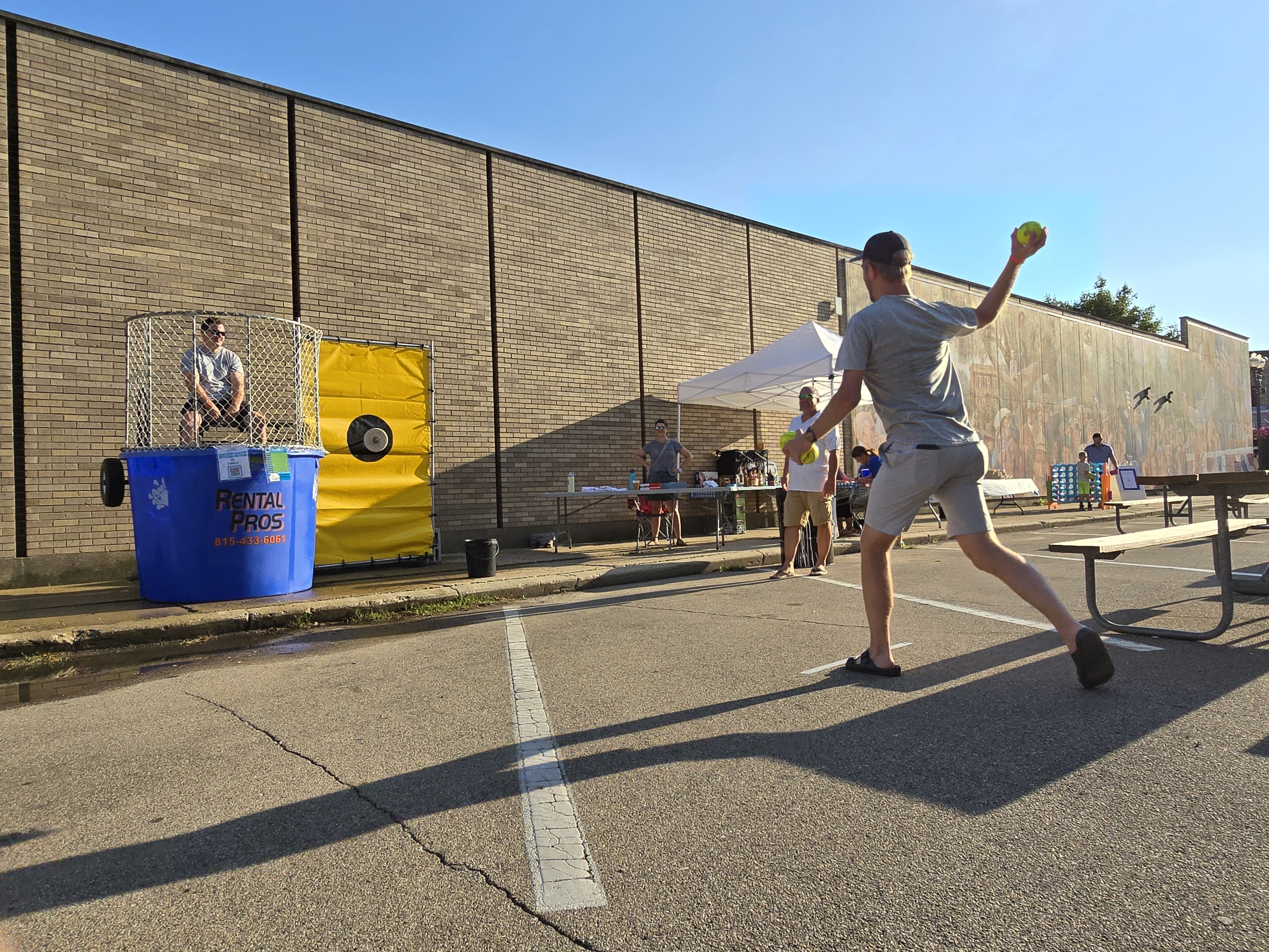 Gentry Nordstrom, of Ottawa, rears back a pitch that hits the target of the dunk tank Wednesday, July 31, 2024, dunking Fire Chief Brian Bressner during the Rock the Block event on Jackson Street.