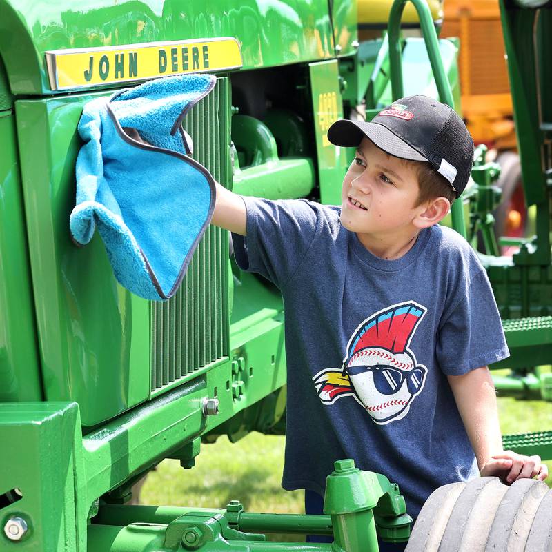 Eli Todd, 10, from Waterman, shines up his grandpa’s 1967 John Deere 4020 tractor on display Saturday, July 15, 2023, at the Waterman Lions Summerfest and Antique Tractor and Truck Show at Waterman Lions Club Park.