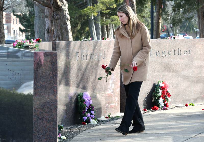 Amy Ogden puts flowers at the base of each stone Wednesday, Feb. 14, 2024, during a ceremony in the Peaceful Reflection Garden near Cole Hall at NIU honoring the victims of the 2008 shooting on campus in DeKalb. Wednesday marked 16 years since the deadly shooting took place on campus which took the lives of five people.