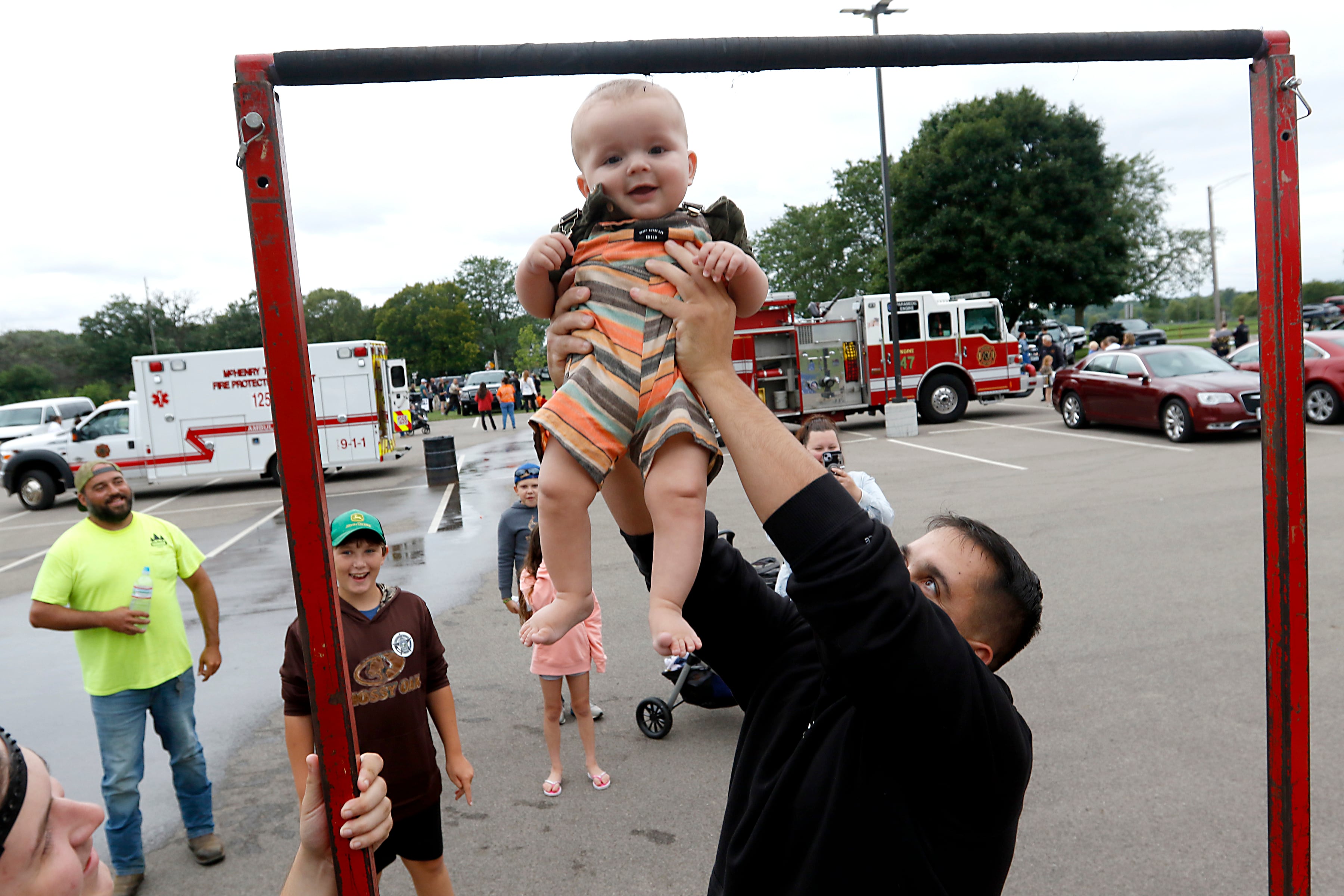 Harlow Speciale, 7 months, is lifted up by his dad. Kenny, at a pull-up station during a National Night Out event Tuesday, Aug. 6, 2024, at Petersen Park in McHenry.