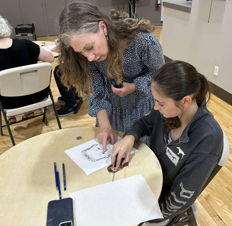 Retired forensic artist Bethe Hughes of Dixon gives some tips to Ashlyn Foster, 17, of Savanna, during a workshop on forensic art at the Coliseum Museum of Art, Antiques, and Americana in Oregon on Saturday, Aug. 17, 2024. Hughes worked as a special agent for the Illinois State Police for 20 years before retiring.